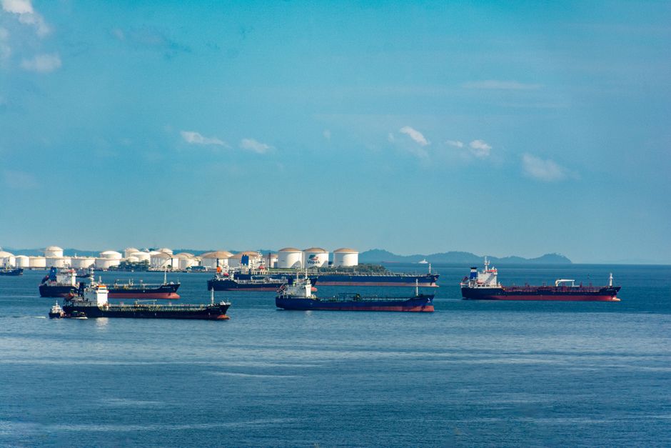 Cargo ships docked near oil storage along a coastline