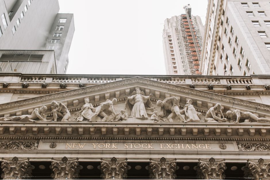The ornate stone facade of the New York Stock Exchange building, with carved reliefs and architectural details.