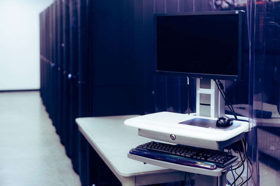 A computer and server racks represent the infrastructure spending behind the AI investment cycle.