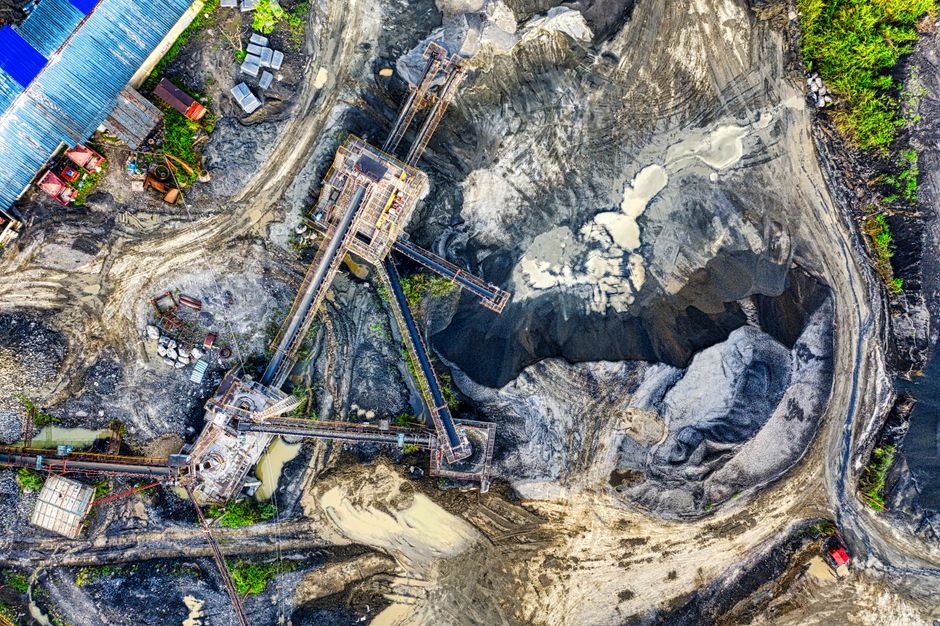 Aerial view of an industrial mining excavation site showing heavy machinery and open-pit operations.