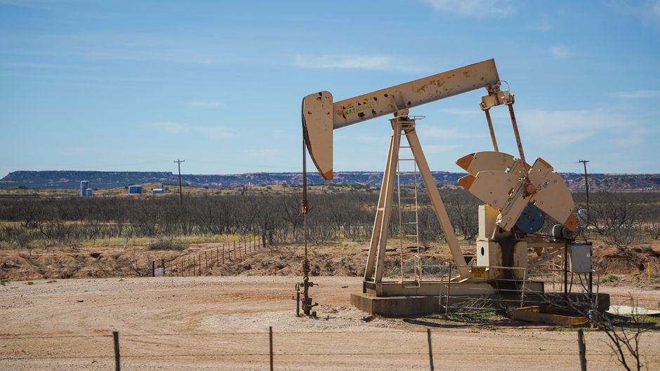 Oil production infrastructure in a desert landscape as geopolitical supply risks test corporate margins.