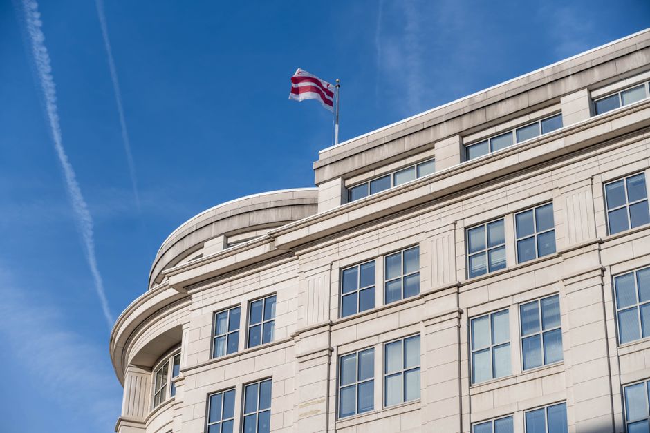 Exterior of a federal building in Washington DC with a flag waving against a clear sky