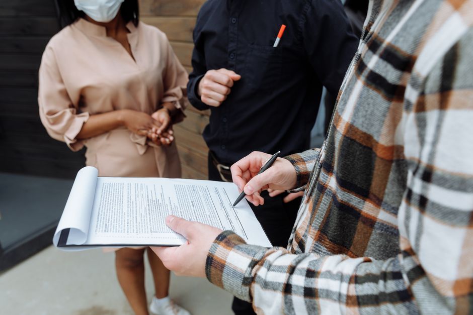 Three professionals in an office setting reviewing and signing a document, symbolizing corporate transactions and public offerings.