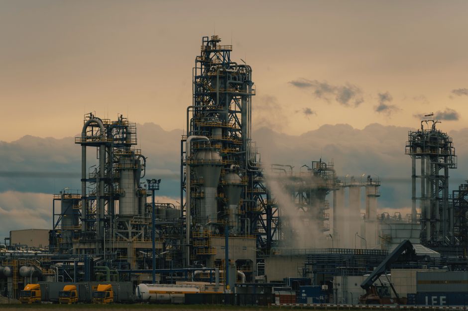 Industrial oil refinery with distillation towers and pipes operating at dusk