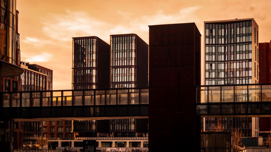 Skyline of modern buildings with walkway at sunset, showcasing urban architecture.