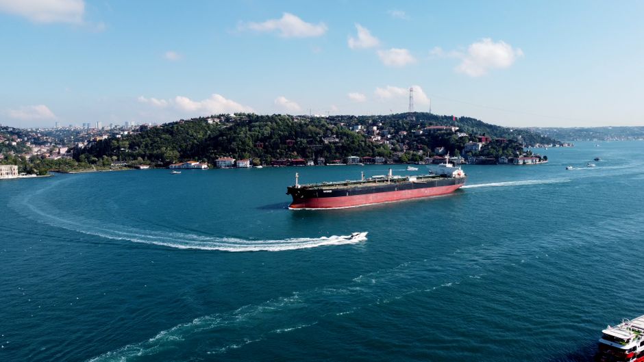 Aerial view of a large cargo ship navigating through a narrow strait with land on both sides