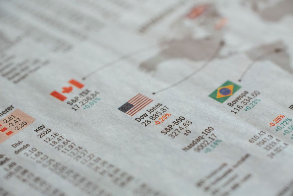 Detailed close-up of a newspaper displaying global financial market statistics and country flags.